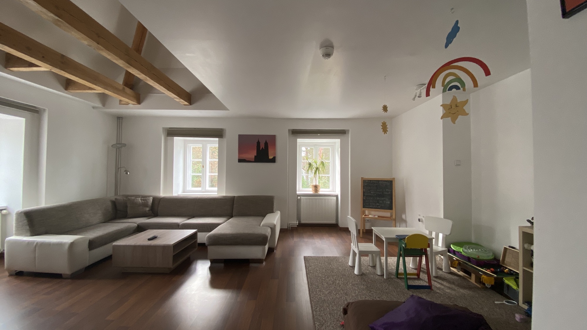 Heller Spiel- und Aufenthaltsraum mit Sofa und Kinderm&ouml;beln