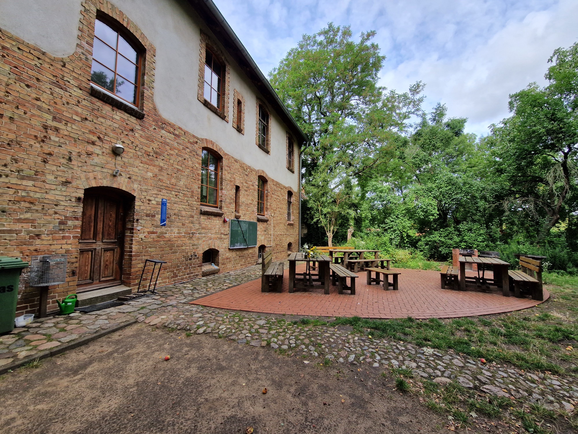 Sitzplatz mit Tischen und B&auml;nken hinter dem Landheim